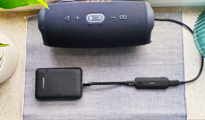 Liion Power's Leo adapter plugged into a portable power bank and a charging speaker.